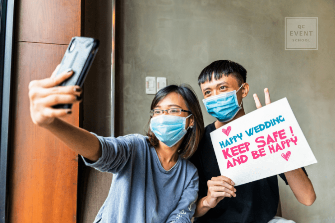 young couple wearing masks and wishing couple happy wedding over video call