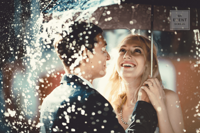 Bride and groom standing under umbrella in the rain