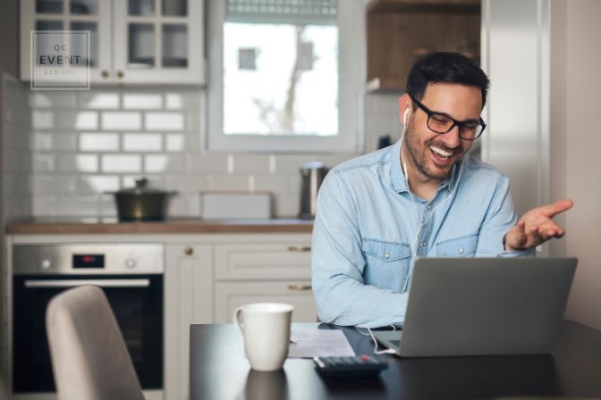 Adult male event planner working at desk from home, talking to client on laptop