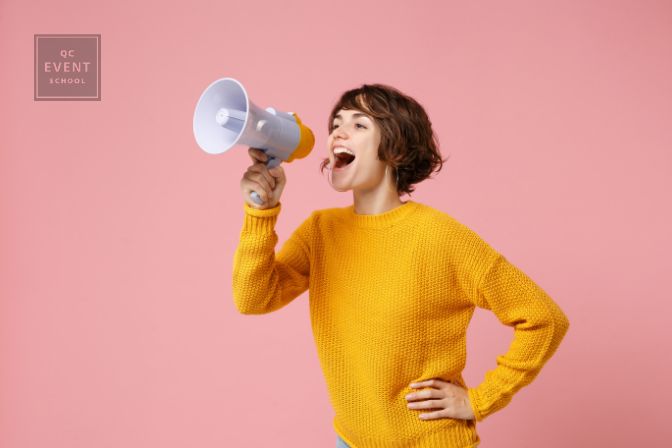 Funny young brunette woman girl in yellow sweater posing isolated on pastel pink wall background studio portrait. People sincere emotions lifestyle concept. Mock up copy space. Screaming in megaphone