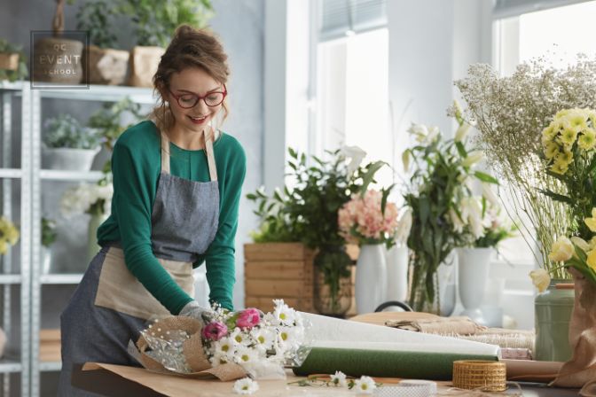 Young smiling florist working in her cozy flower shop