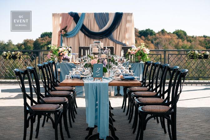 Wedding catered event setting, flowers, candles, white plates, blue napkins, wooden tables, Event decoration, outdoors, summer time