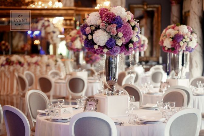 Round dinner table decorated with pink and violet hydrangeas stands in luxurious restaurant