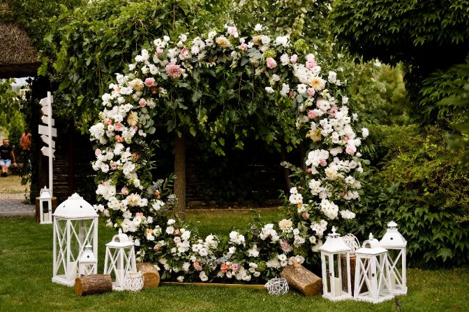 Beautiful wedding set up. Area of the wedding ceremony. Round arch, white chairs decorated with flowers, greenery. Cute, trendy rustic decor. Part of the festive decor, floral arrangement. Wedding planning business.