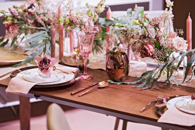 Table setting in pink color, for a wedding or other event, wine glasses, plates, spoons, forks, flowers and vases. Party planner article.
