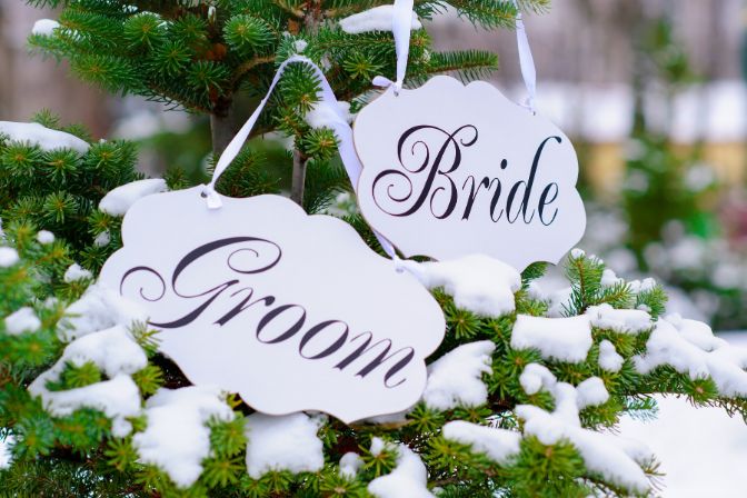 Bride and groom decoration boards hanging on the fir-tree. Winter wedding article.