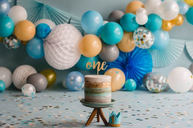 Photo Studio of One Birthday Party or firts birthday cake with Blue and white Ballons with colorful confetti . Cake smash. One year. Balloon garlands.